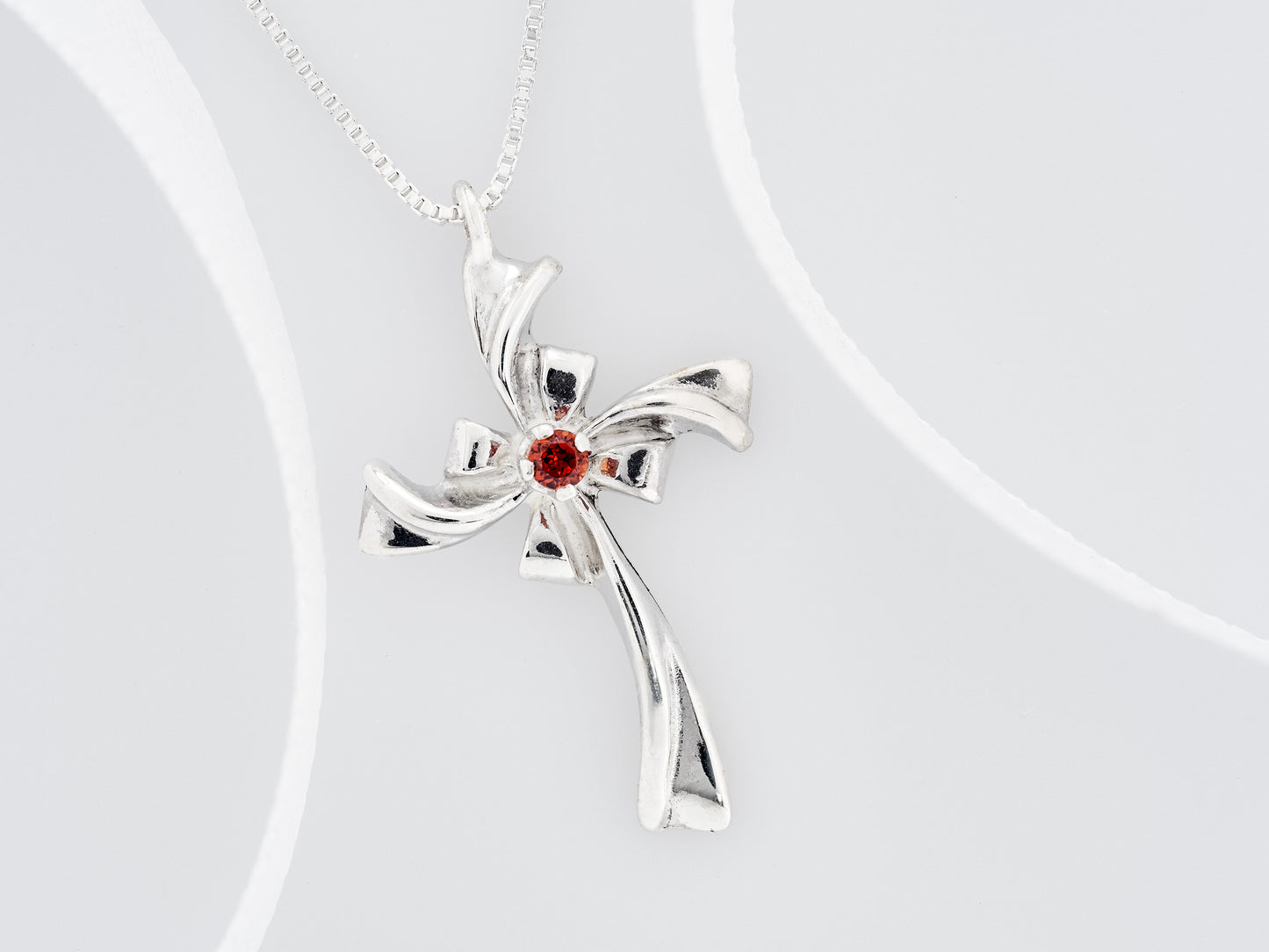 Red Garnet Silver Ribbon Cross Necklace. Handmade, sterling silver pendant with a natural, round faceted, garnet gem.